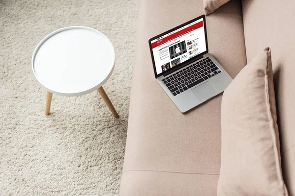 Высокий угол зрения ноутбука, стоящего на уютном диване с bbC сайт на экране — стоковое фото