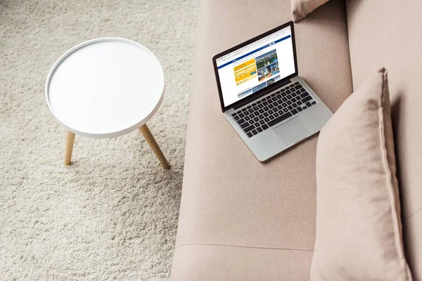 High angle view of laptop standing on cozy couch with booking website on screen — Stock Photo