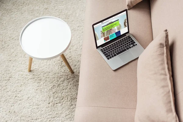 Высокий угол зрения ноутбука, стоящего на уютном диване с bbC сайт на экране — стоковое фото
