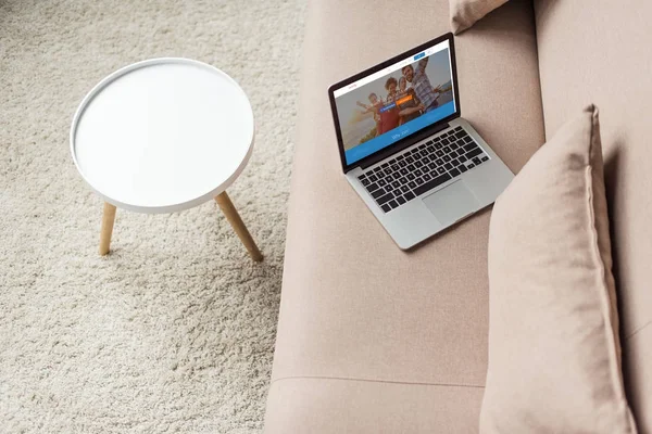 Vue grand angle de l'ordinateur portable debout sur un canapé confortable avec site de couchsurfing à l'écran — Stock Photo