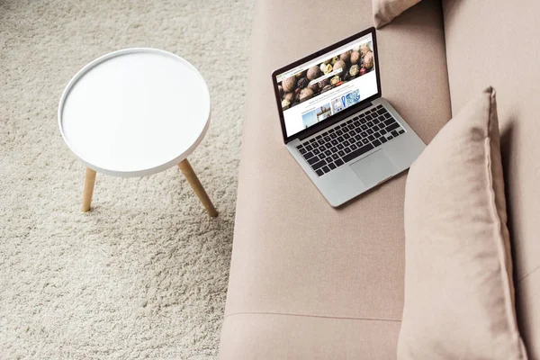 High angle view of laptop standing on cozy couch with shutterstock website on screen — Stock Photo