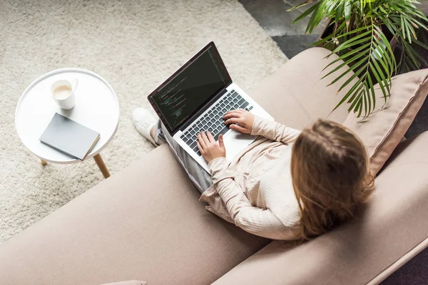 Vista de ángulo alto de la joven desarrolladora de codificación con ordenador portátil en el sofá - foto de stock