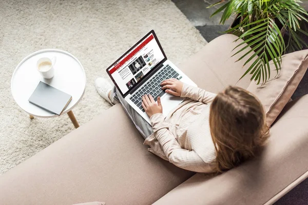 Visão de alto ângulo da mulher em casa sentado no sofá e usando laptop com o site bbc na tela — Fotografia de Stock