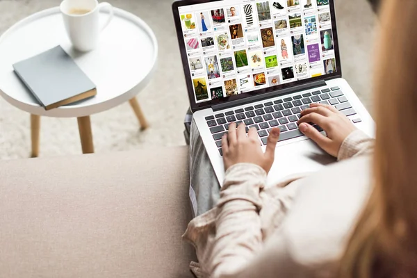 Cropped shot of woman at home sitting on couch and using laptop with pinterest website on screen — Stock Photo
