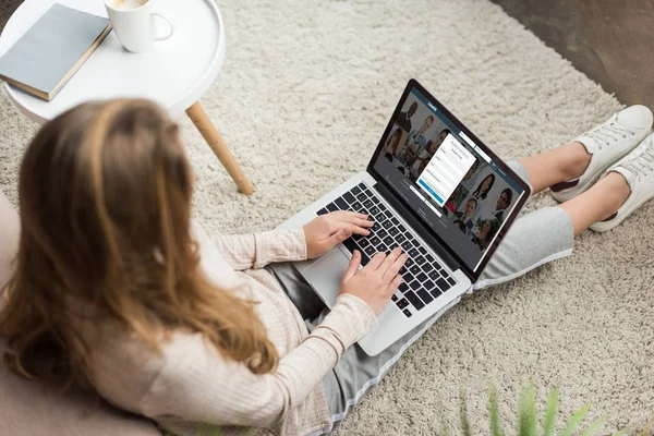 High angle view of woman at home sitting on floor and using laptop with linkedin website on screen — Stock Photo