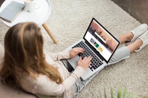 Vista de alto ângulo da mulher em casa sentado no chão e usando laptop com shutterstock homepage na tela — Fotografia de Stock