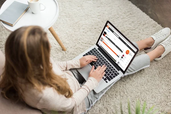 Vue grand angle de la femme à la maison assise sur le sol et utilisant un ordinateur portable avec site Web soundcloud à l'écran — Photo de stock