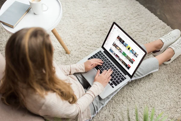 Vista de ángulo alto de la mujer en casa sentado en el suelo y el uso de la computadora portátil con el sitio web de youtube en la pantalla - foto de stock
