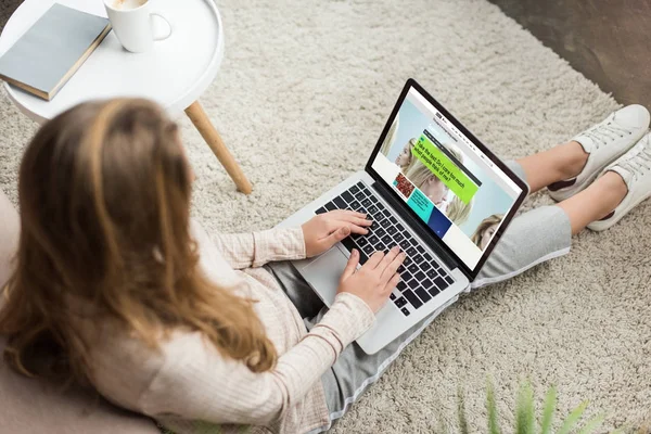 High angle view of woman at home sitting on floor and using laptop with bbc website on screen — Stock Photo