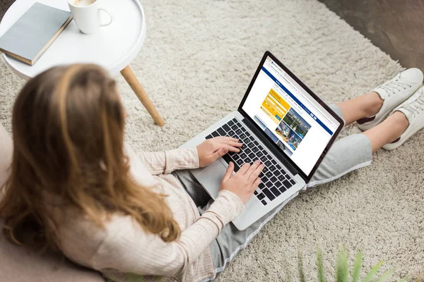 High angle view of woman at home sitting on floor and using laptop with booking website on screen — Stock Photo