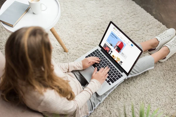 High angle view of woman at home sitting on floor and using laptop with ebay website on screen — Stock Photo