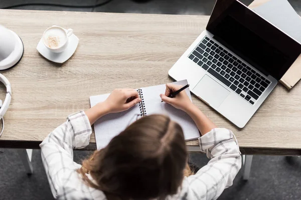 Top view of young woman writing in notebook at workplace — Stock Photo