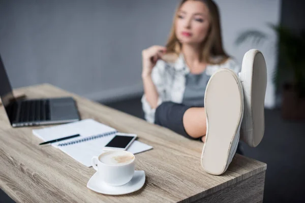 Junge Geschäftsfrau entspannt sich am Arbeitsplatz mit Füßen auf dem Tisch — Stockfoto