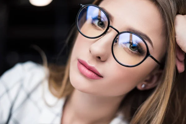 Close-up portrait of beautiful young woman in eyeglasses looking at camera — Stock Photo