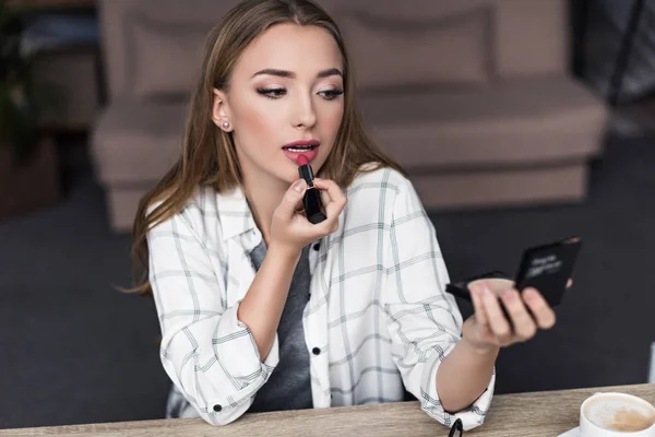 Attraente giovane donna che fa il trucco con rossetto rosa — Foto stock