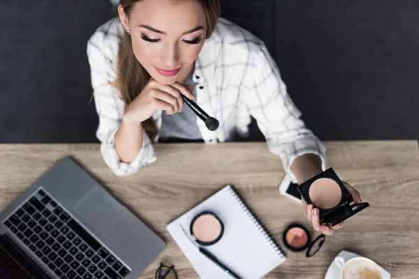Top view of thoughtful young woman doing makeup at workplace — Stock Photo