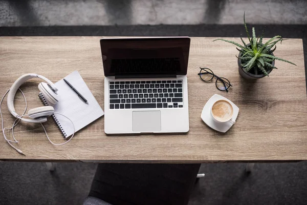 Верхний вид ноутбука с чашкой кофе и наушниками на современном рабочем месте — стоковое фото