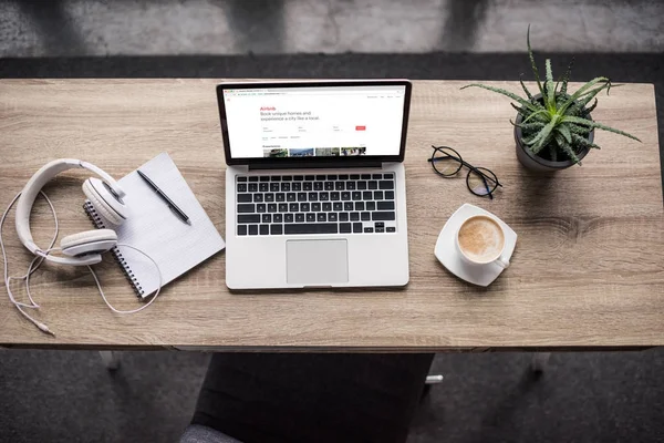 Vue du haut de l'ordinateur portable debout sur le lieu de travail moderne avec le site Web airbnb à l'écran — Photo de stock