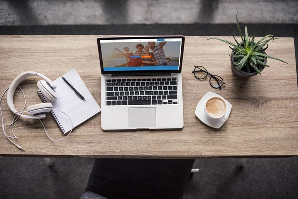 Top view of laptop standing at modern workplace with couchsurfing website on screen — Stock Photo