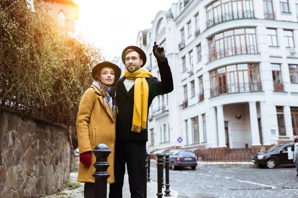 Young beautiful couple catching taxi on city street — Stock Photo