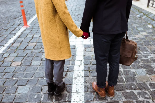 Imagen recortada de pareja en traje de otoño cogido de la mano - foto de stock