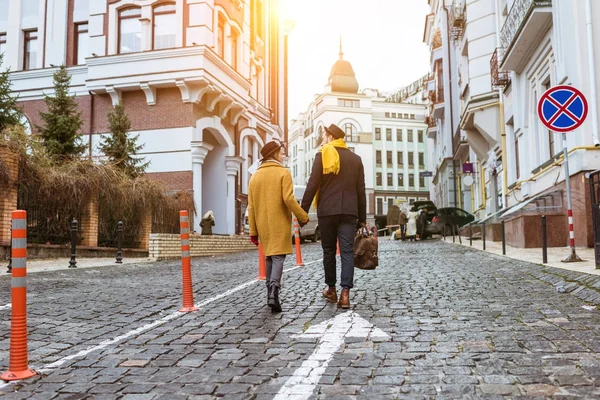 Vista trasera de pareja cogida de la mano y caminando por la calle - foto de stock