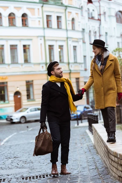Молодая привлекательная пара, держащаяся за руки и идущая по улице — стоковое фото