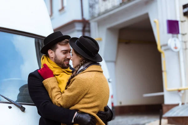 Hermosa pareja joven abrazándose en traje de otoño al lado del coche - foto de stock