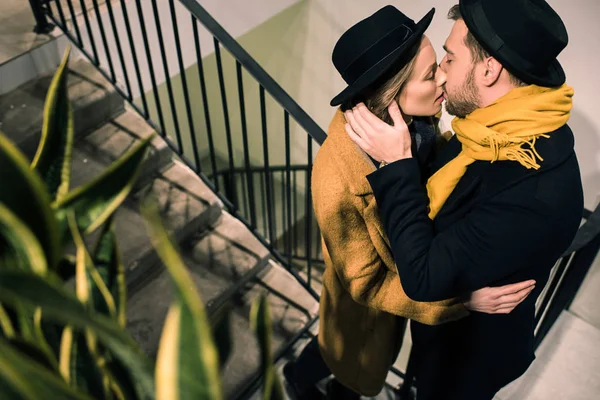 Joven pareja atractiva besándose en escaleras - foto de stock
