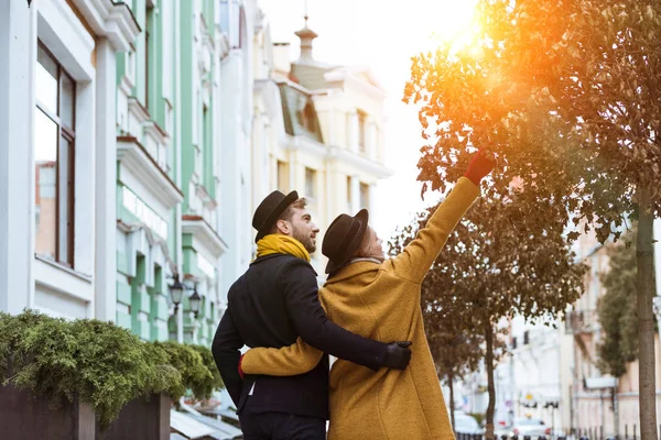 Rückansicht eines jungen Paares, das sich umarmt und auf der Straße spaziert — Stockfoto