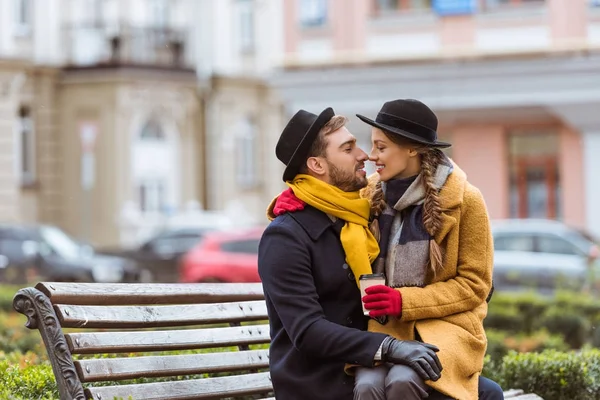 Belo casal sentado no banco com xícara de café — Fotografia de Stock