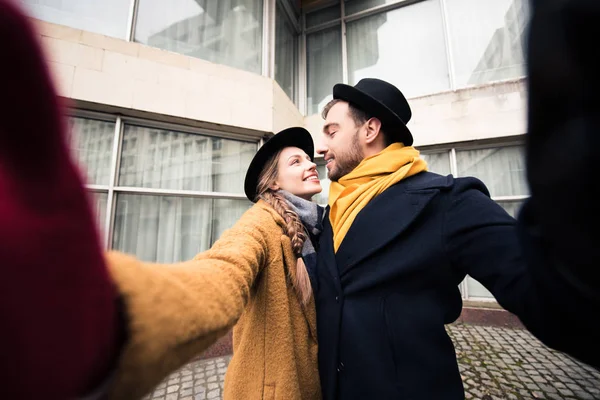 Feliz abrazo joven pareja tomando selfie delante de la construcción - foto de stock