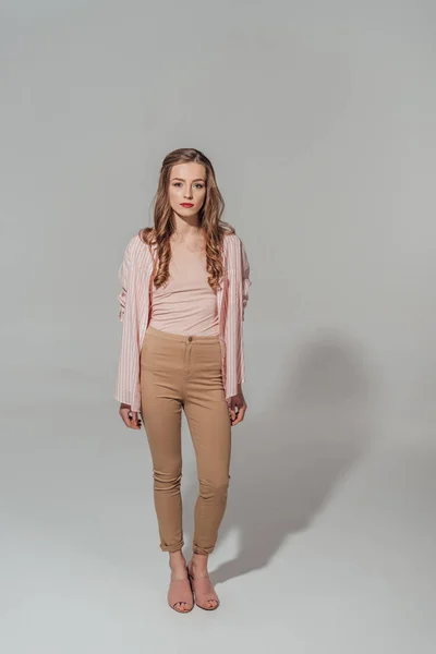 Vista completa de la hermosa mujer joven en la mirada a la cámara aislada en gris - foto de stock