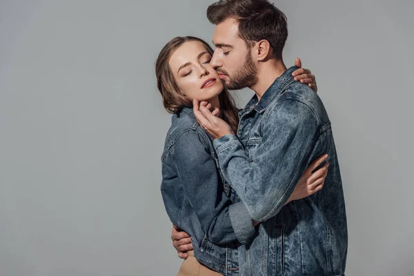 Seductora pareja joven con los ojos cerrados abrazándose y tocándose aislados en gris — Stock Photo