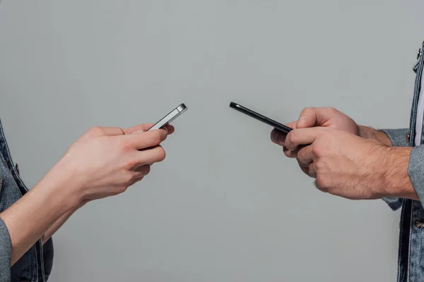 Schnappschuss eines jungen Paares mit Smartphones isoliert auf grau — Stockfoto