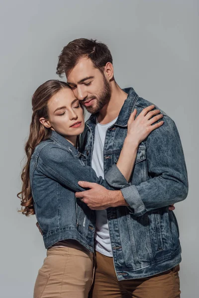 Hermosa feliz joven pareja con los ojos cerrados abrazo aislado en gris - foto de stock