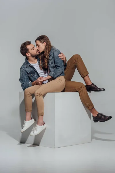 Seductora pareja joven abrazándose y besándose en gris - foto de stock