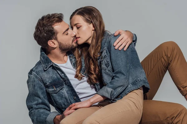 Seductive young couple kissing isolated on grey — Stock Photo