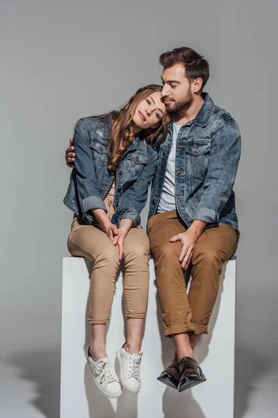 Bella giovane coppia innamorata seduta insieme sul grigio — Foto stock