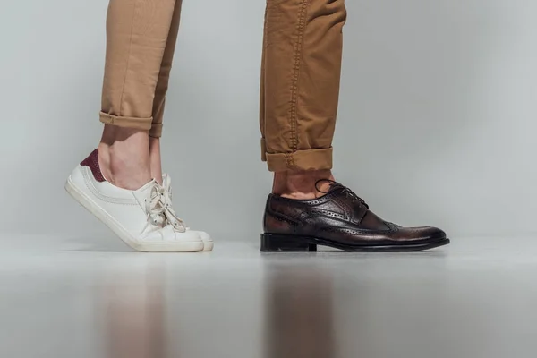 Обрезанный кадр мужских и женских ног в обуви с отражением на сером — стоковое фото