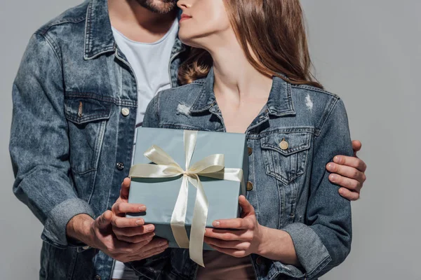 Cropped shot of young man presenting gift box to girlfriend isolated on grey — Stock Photo