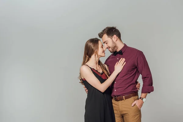Elegante jovem casal sorrindo uns aos outros isolado em cinza — Fotografia de Stock