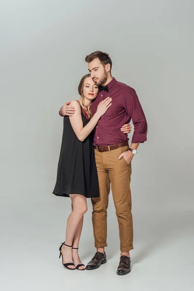 Vista completa de la hermosa pareja joven con estilo en el amor abrazando aislado en gris — Stock Photo