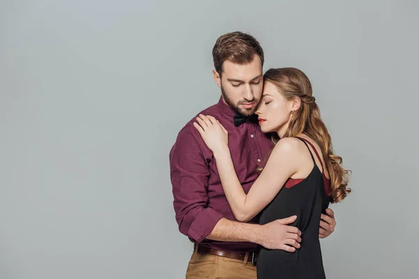 Hermosa pareja joven con estilo en el amor abrazo aislado en gris - foto de stock