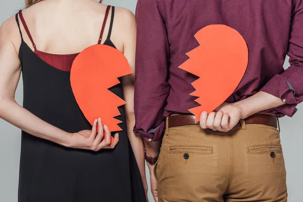 Cropped shot of young couple holding broken heart symbol isolated on grey — Stock Photo