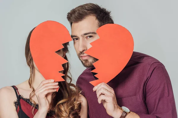 Stylish young couple holding broken heart symbol isolated on grey — Stock Photo