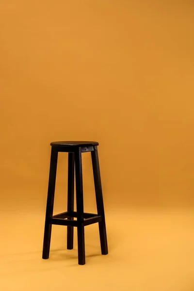 Dunkler Barhocker aus Holz auf orangefarbenem Hintergrund — Stockfoto