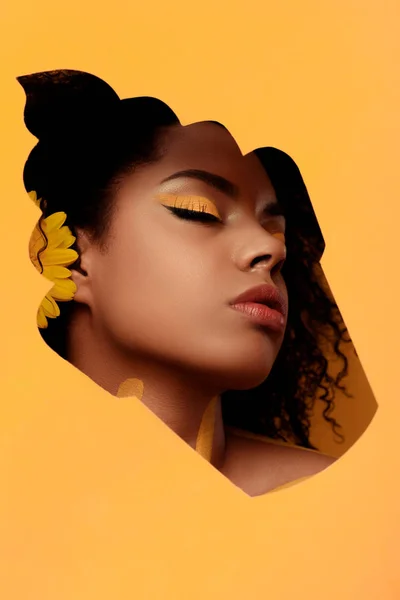 Femme afro-américaine élégante avec maquillage artistique et gerbera dans les cheveux dans le cadre cupcake — Photo de stock