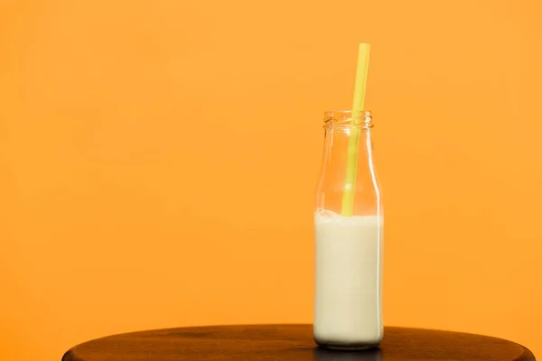 Bebida de leche en botella con paja aislada sobre fondo naranja - foto de stock