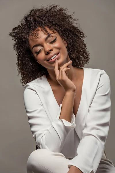 Joven mujer afroamericana sensual en camisa blanca con el dedo en los labios aislado sobre fondo gris - foto de stock